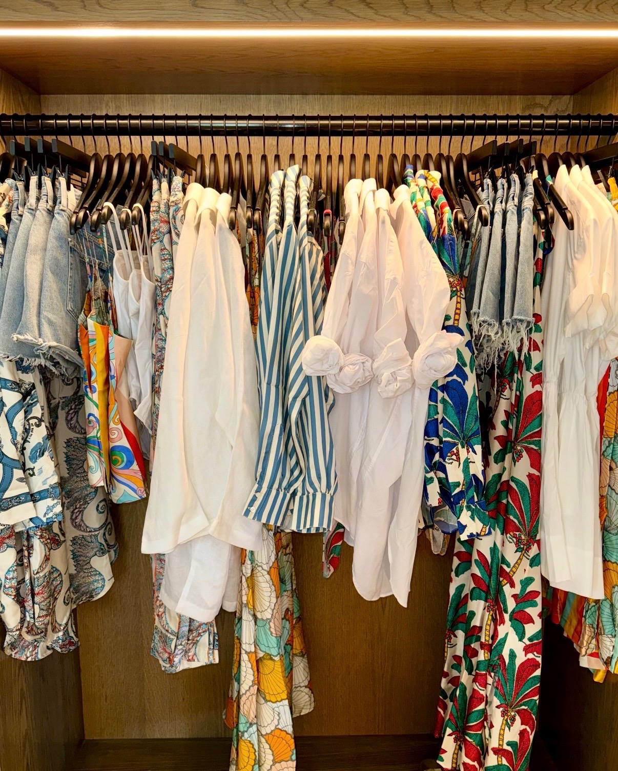 Colorful printed, striped, and white resort apparel arranged in an illuminated Anguilla display