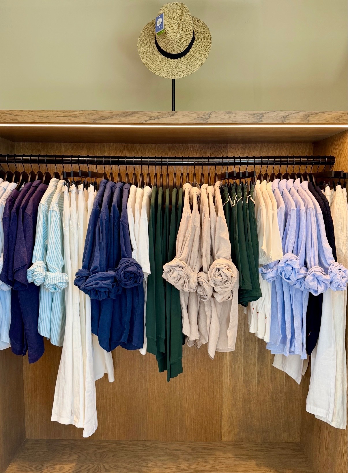 Blue, green, white, and neutral apparel organized on an illuminated rack in Anguilla