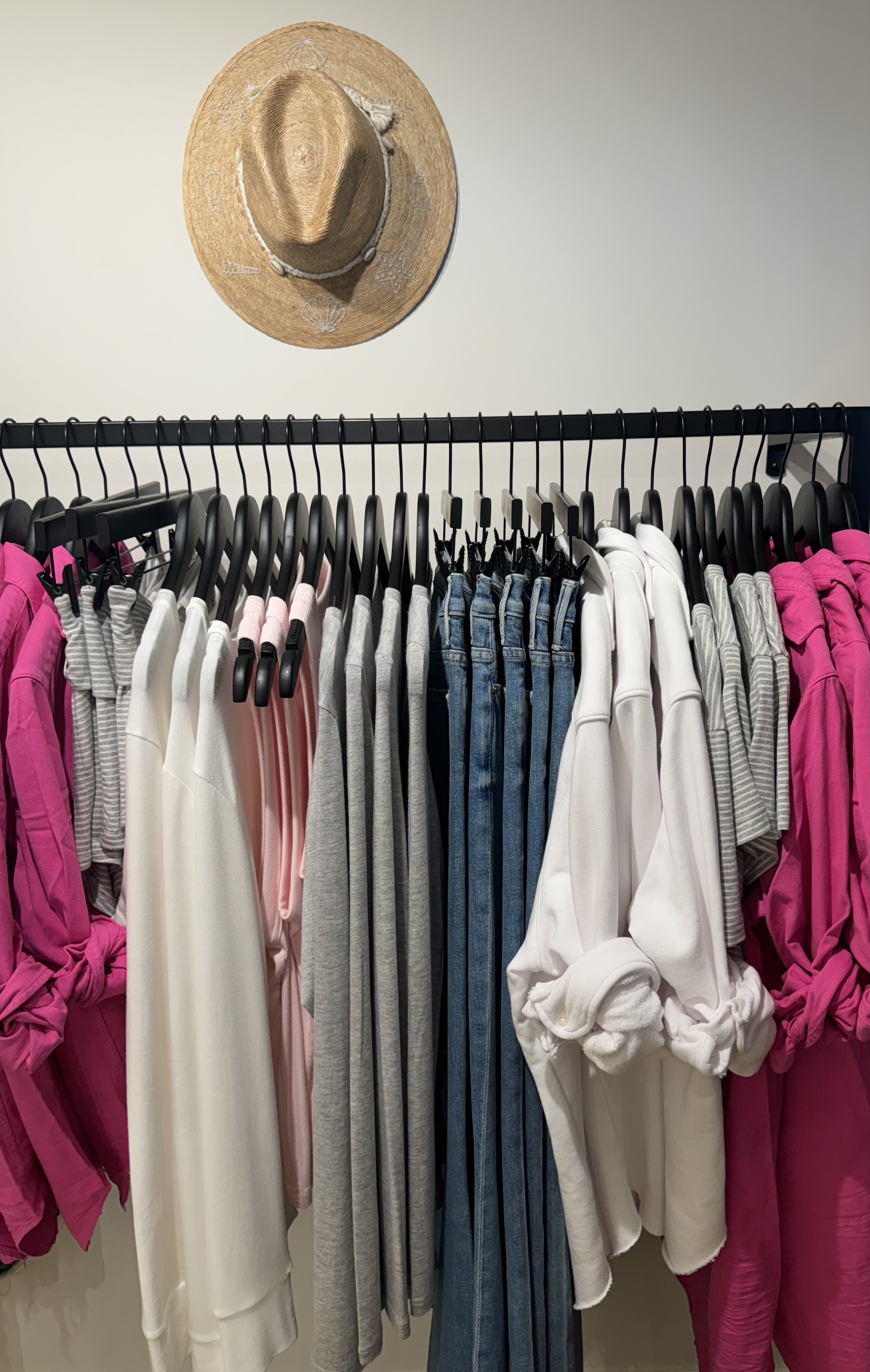 Premium apparel organized by color around a central denim story beneath a sculptural straw hat