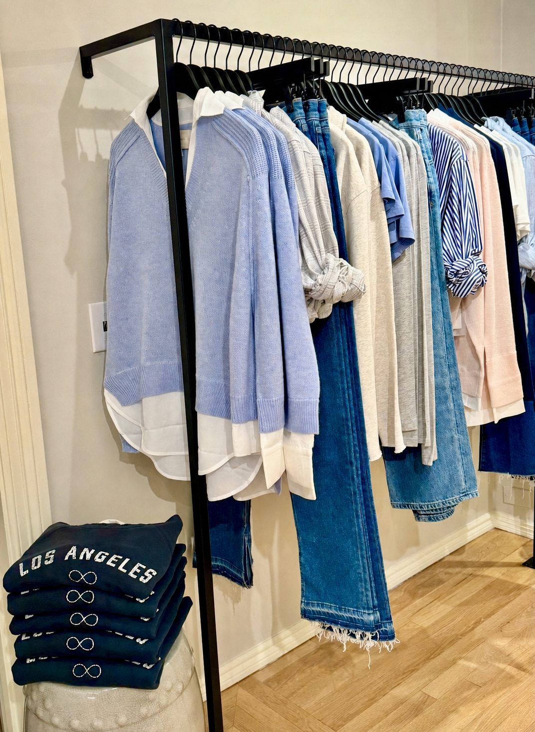 Blue, white, blush, and denim apparel organized on a freestanding boutique rail