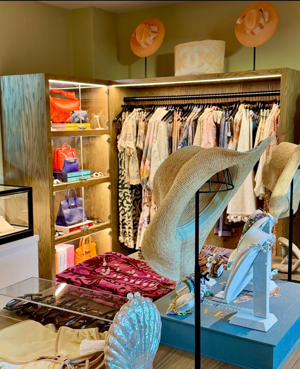 Curated resort boutique with layered accessories, jewelry, apparel, handbags, and sculptural hats