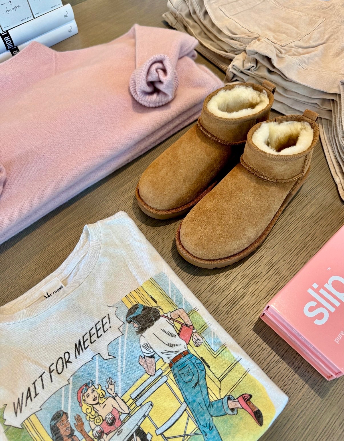 Pink knitwear, neutral apparel, shearling boots, and graphic resort pieces styled on a Nantucket display table