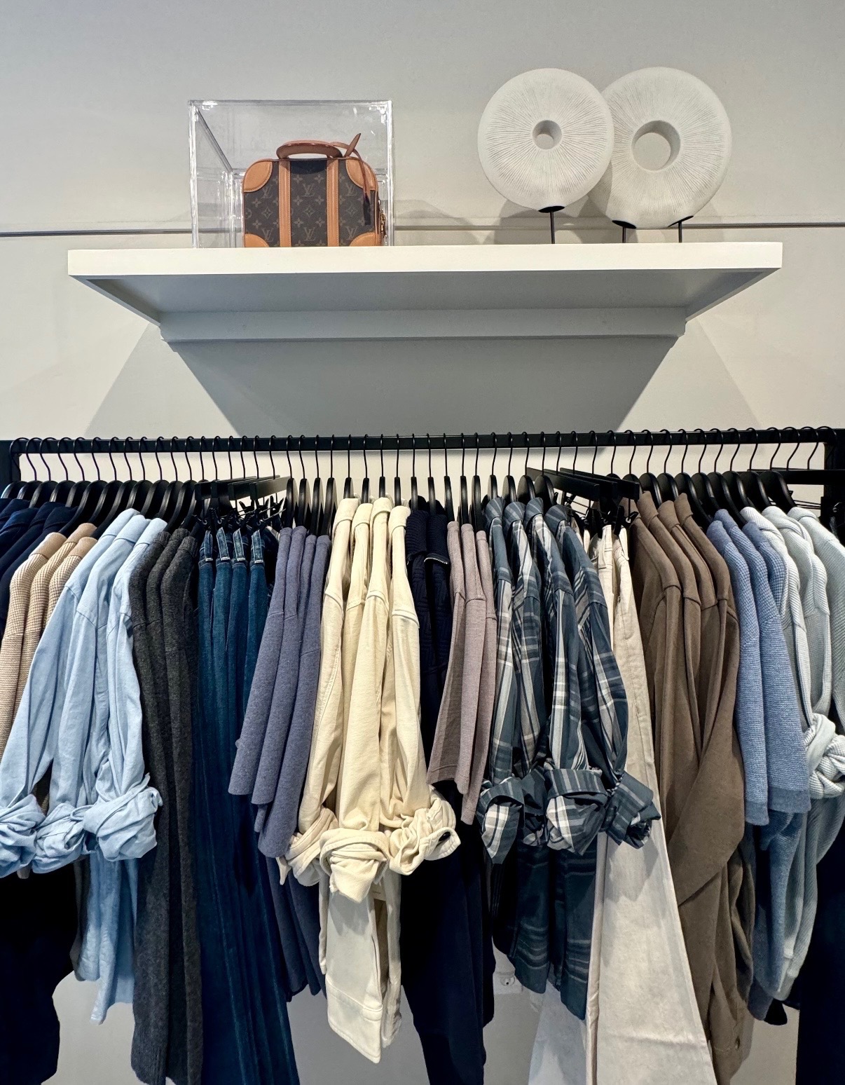 Blue, gray, cream, and plaid apparel displayed beneath sculptural white accessories in Nantucket