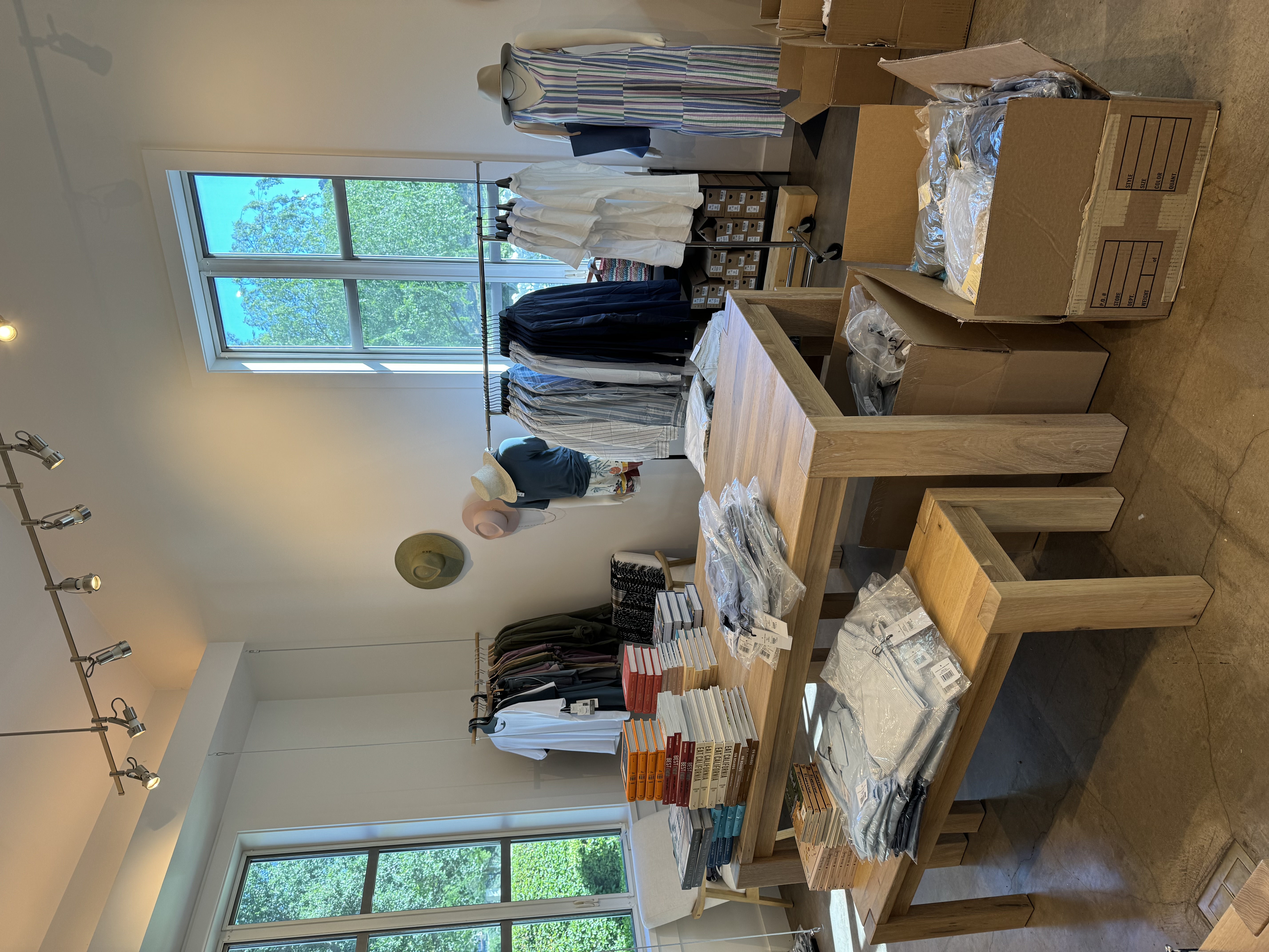 Solage boutique during setup with open cartons, packaged apparel, and unfinished display tables